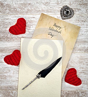 Vintage Valentine`s Day card in withe book with red cuddle hearts ink and quill - top view